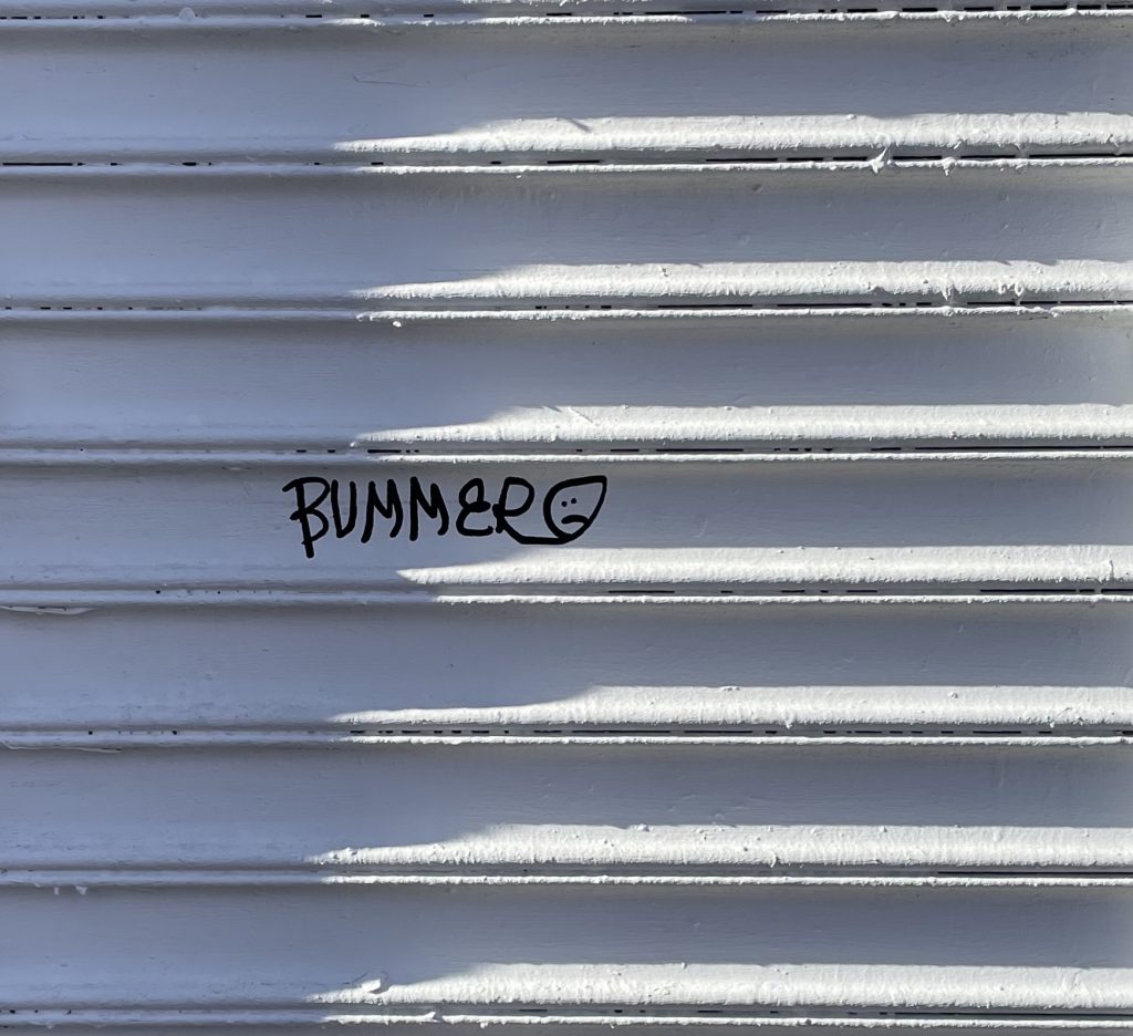 A white shutter door that someone has written "bummer" on