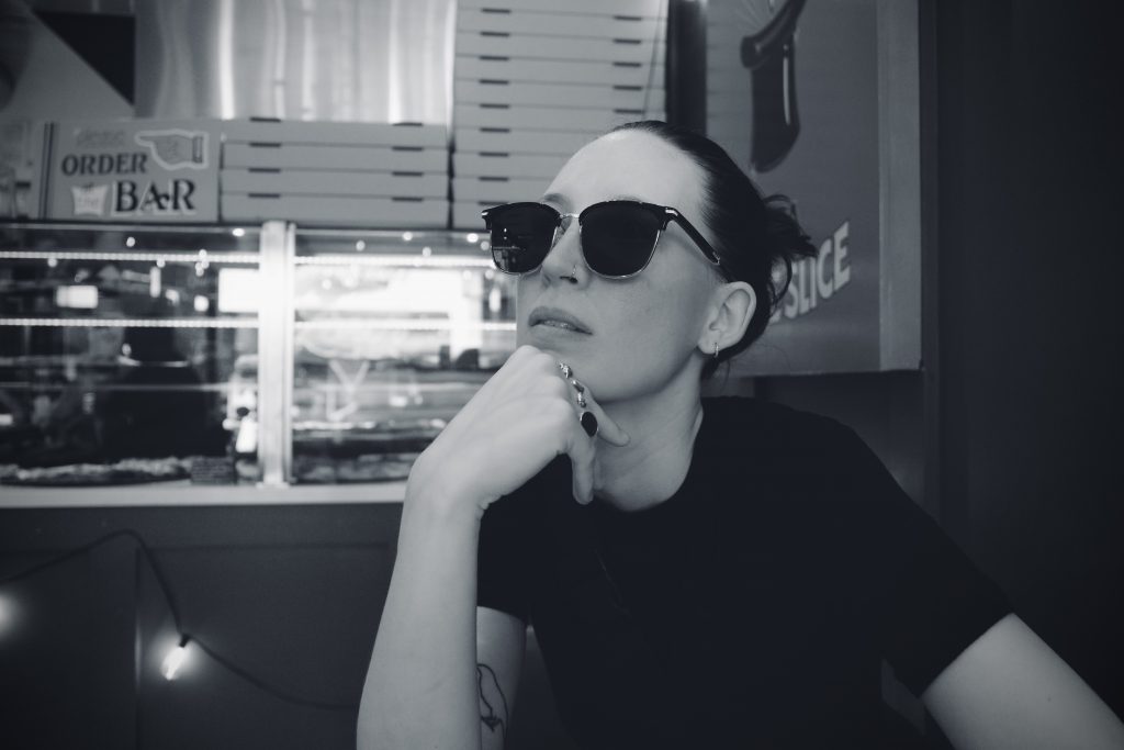 M wearing sunglasses in front of the displays full of pizza in Zorch in Carytown